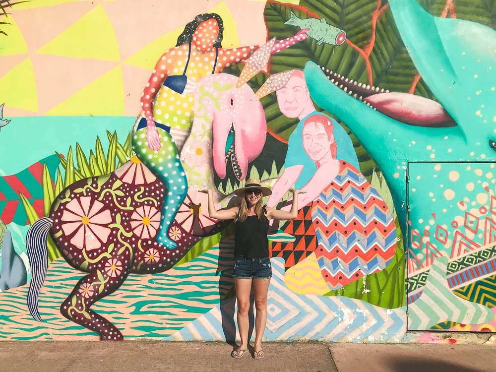 Me standing in front of a colorful street mural on a day trip to Cozumel