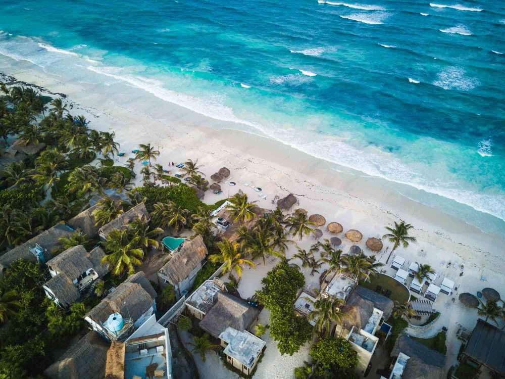 An aerial view of Tulum Mexico beach with buildings and palm trees