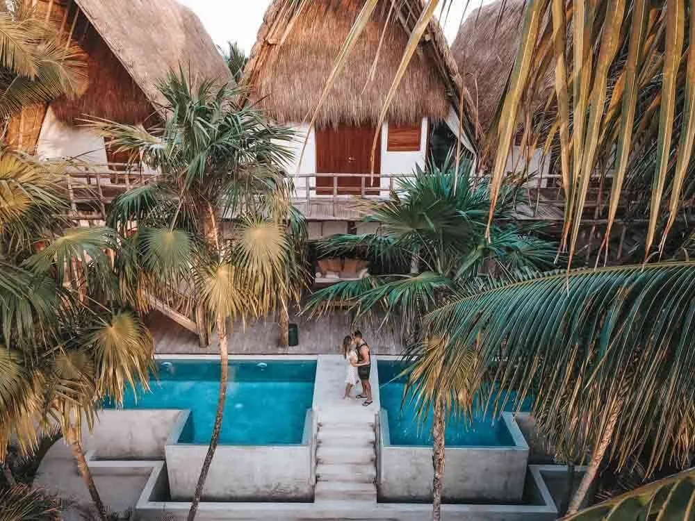 La Valise Hotel in Tulum Mexico with a concrete pool, thatched roof buildings, and palm trees