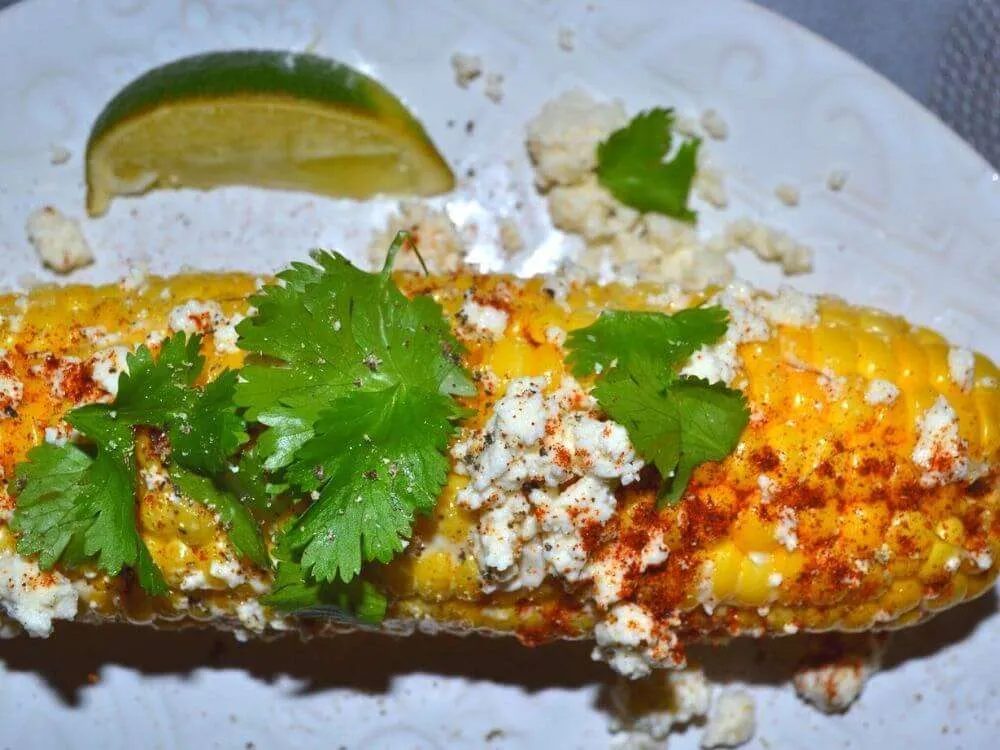 A plate with elote corn and toppings