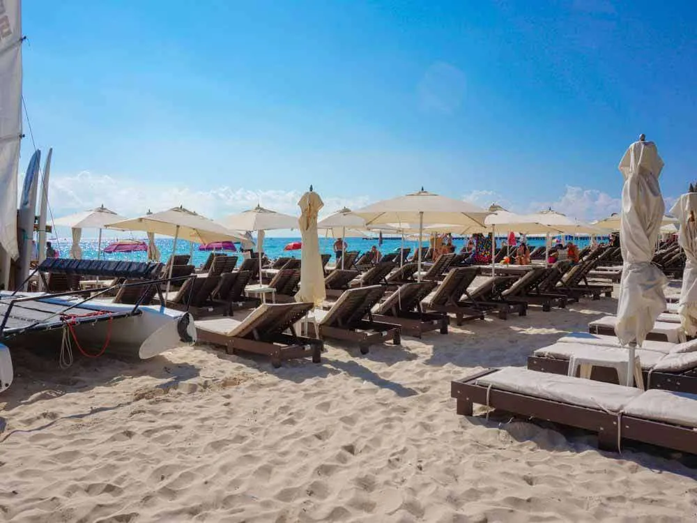 Wooden lounge chairs and beach umbrellas at Tata Beach Club Playa del Carmen
