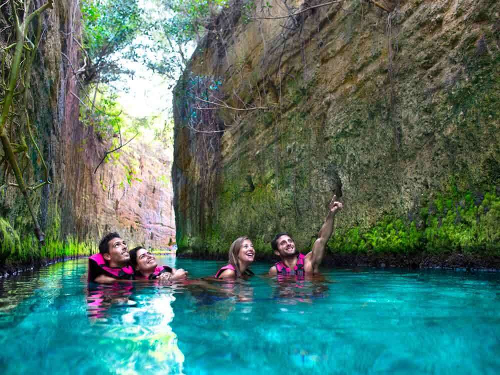 People swimming in underground rivers at Xcaret Park