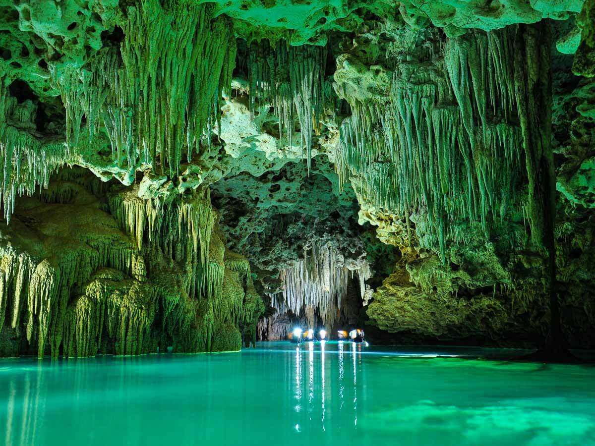 People swimming through Rio Secreto underground caves with stalactites and stalagmites