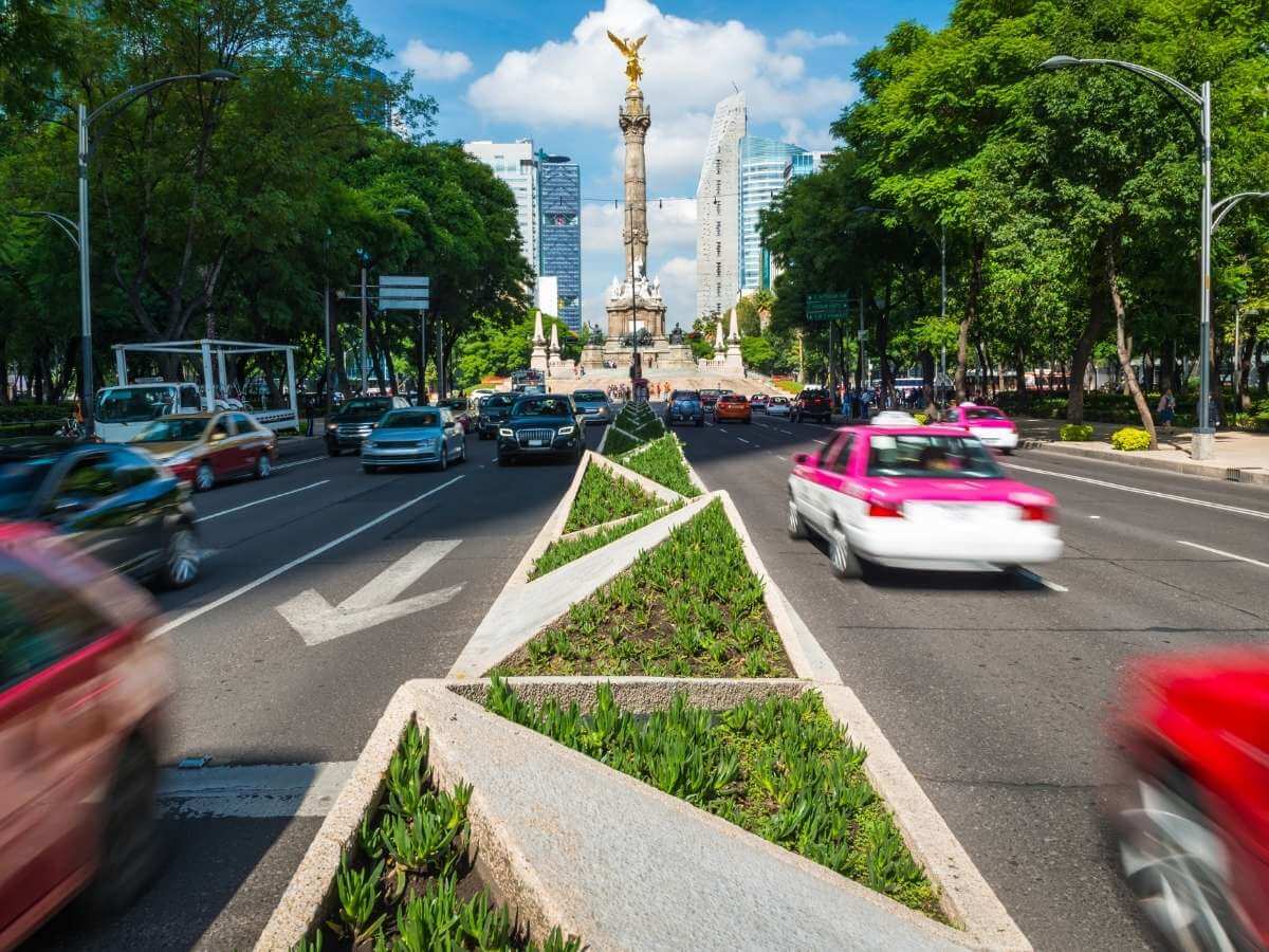 Paseo de la Reforma street in Mexico City with cars and taxis and the Angel of Independence statue in the background
