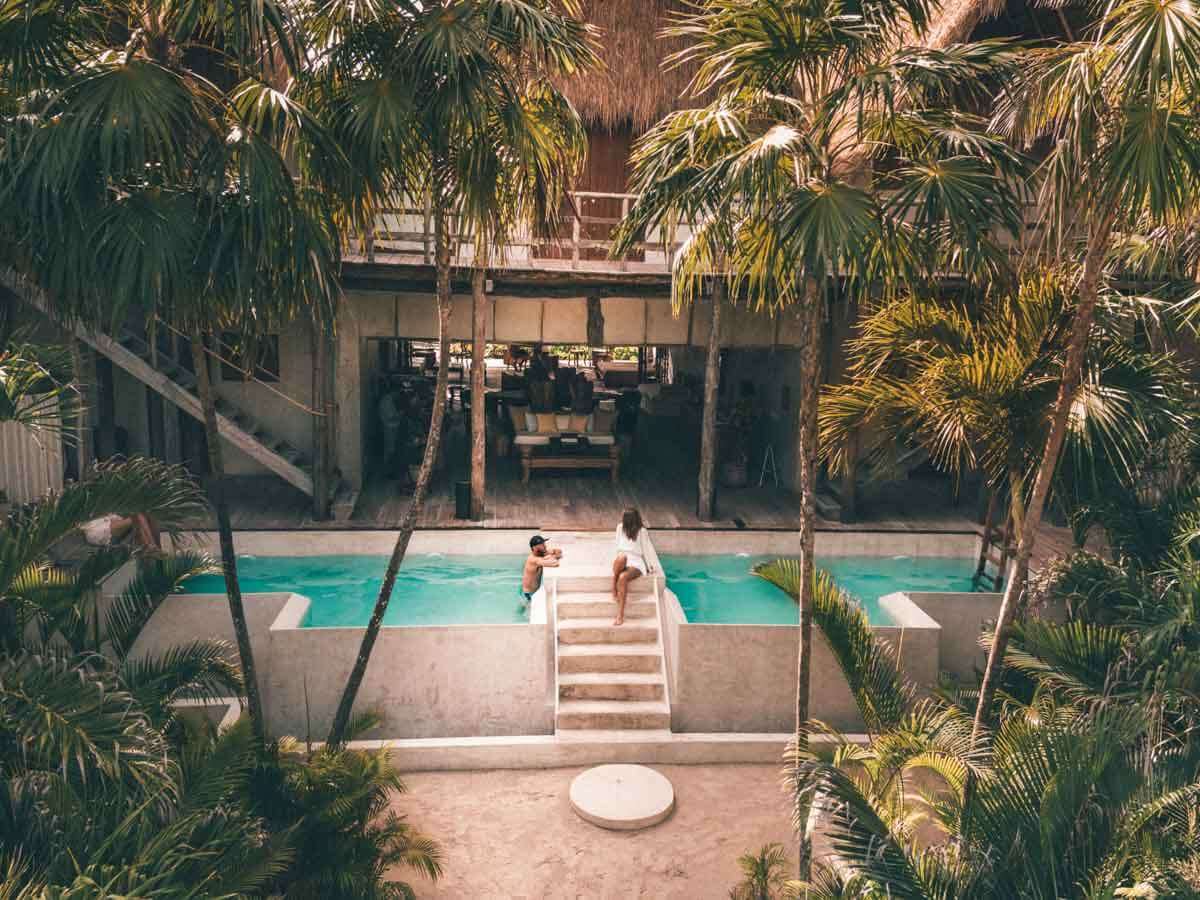 A pool at a hotel in Tulum Mexico surrounded by palm trees