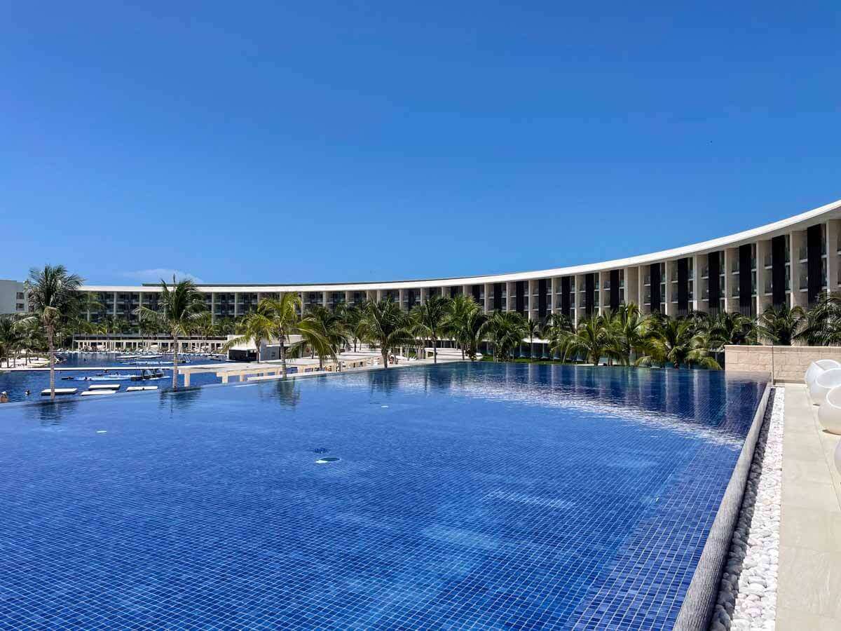 A large infinity pool at Barcelo Maya Riviera with a building next to it