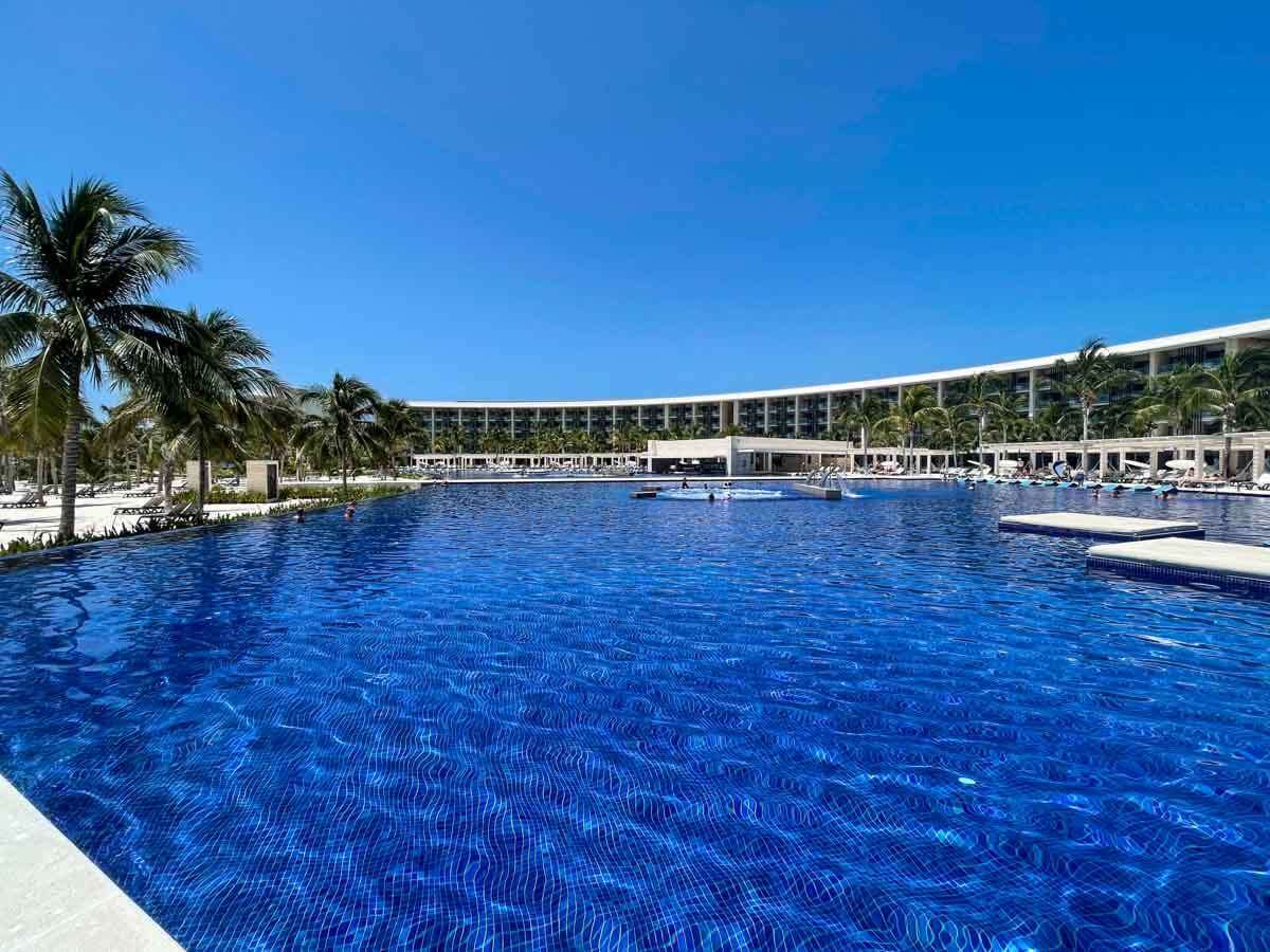 An infinity pool at Barcelo Maya Riviera with palm trees and a building