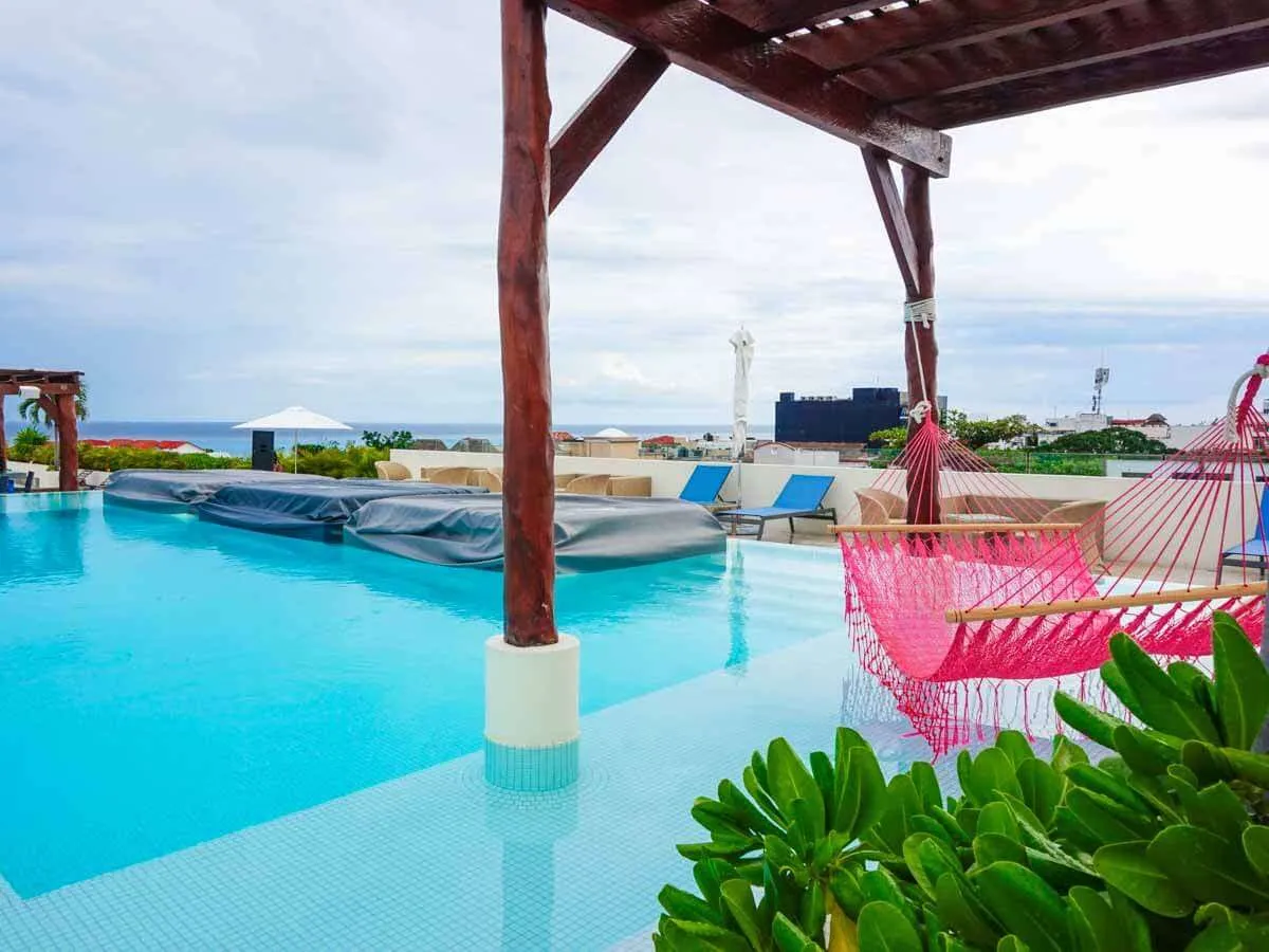 A pink hammock hanging over the rooftop pool at the Palm at Playa hotel