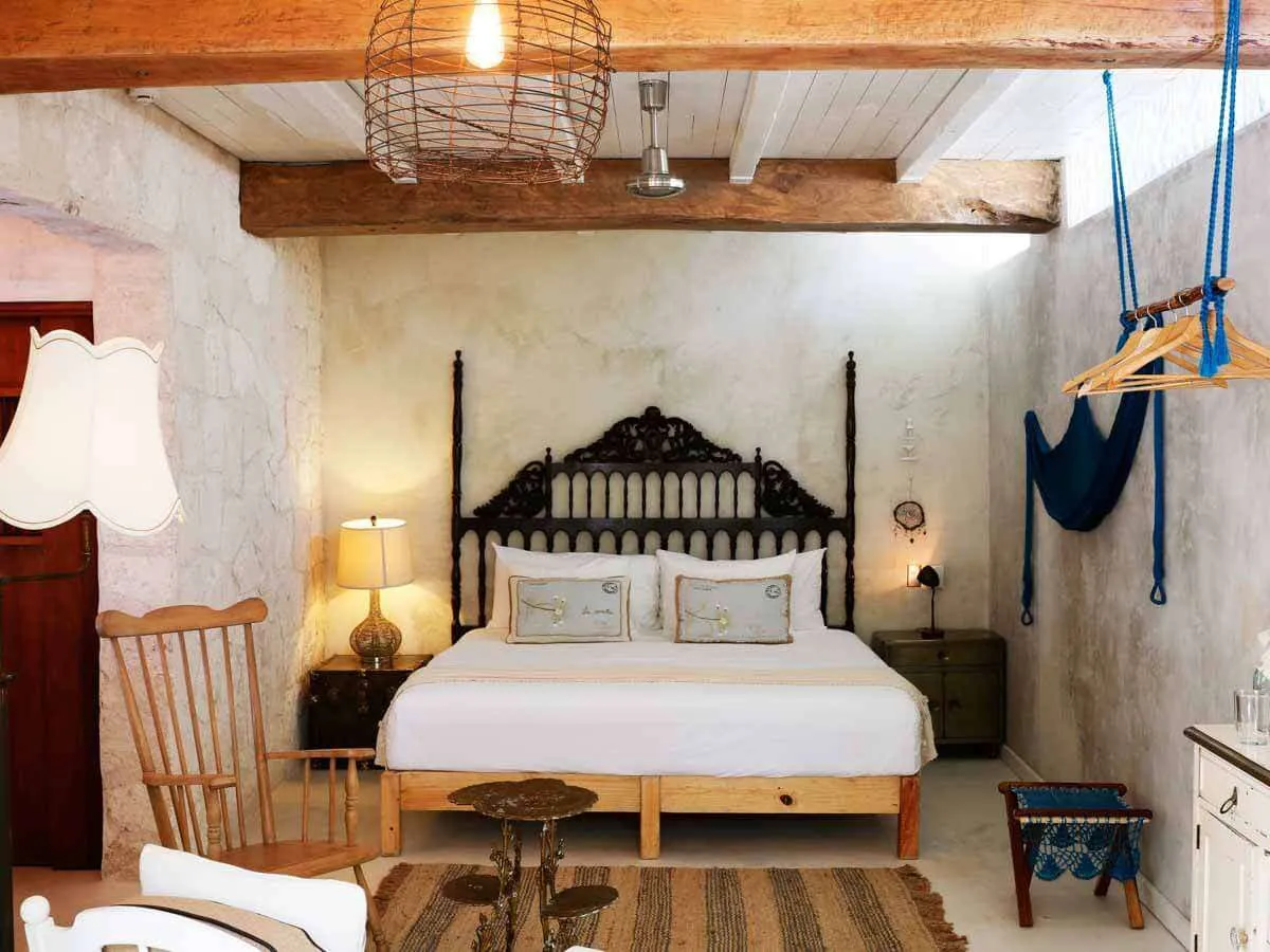 A guestroom with a kind sized bed and rustic furniture at Hotel La Semilla, the best boutique hotel in Playa del Carmen