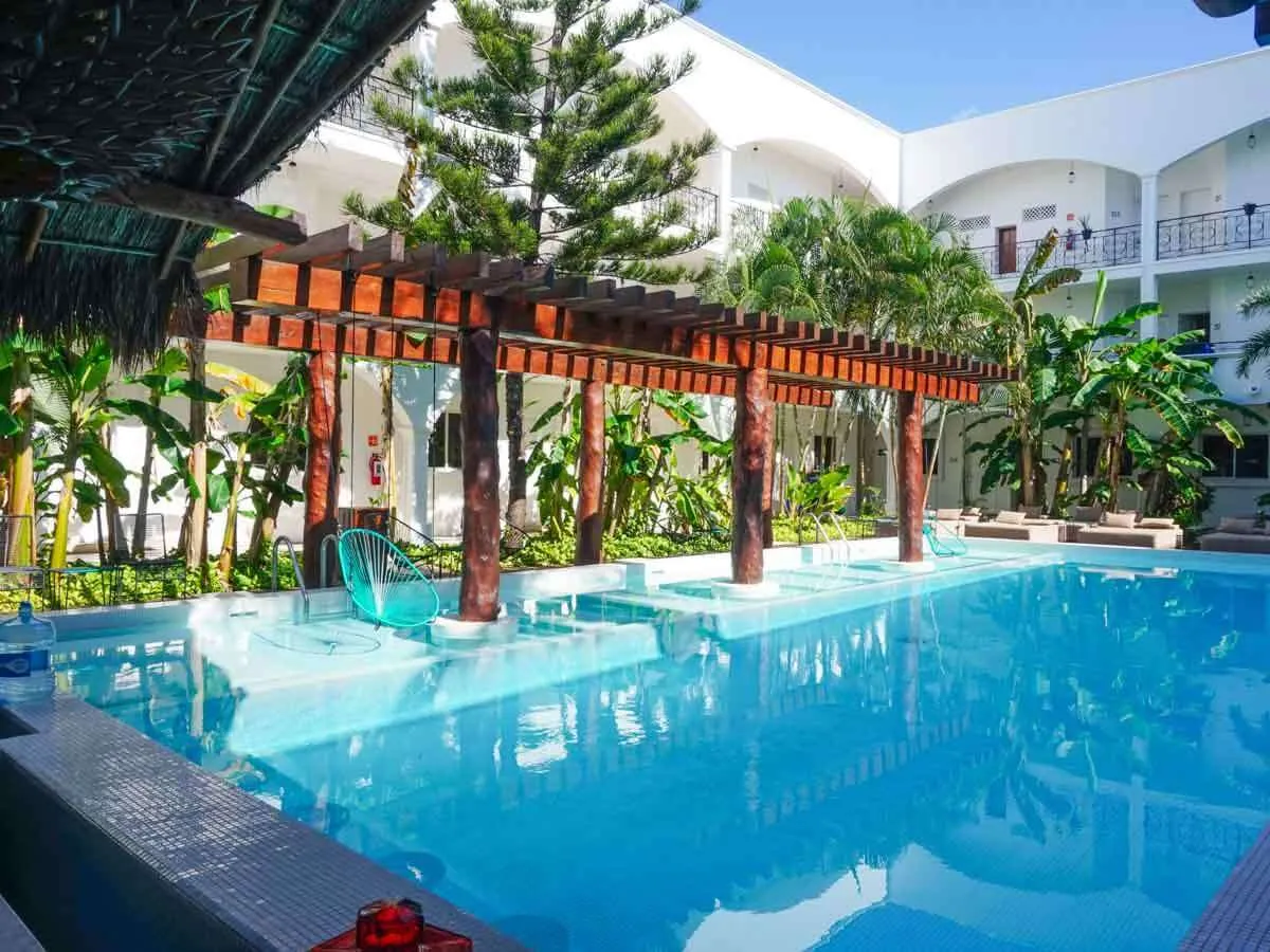 A courtyard pool at Hotel HM Playa del Carmen with chairs hanging over the water