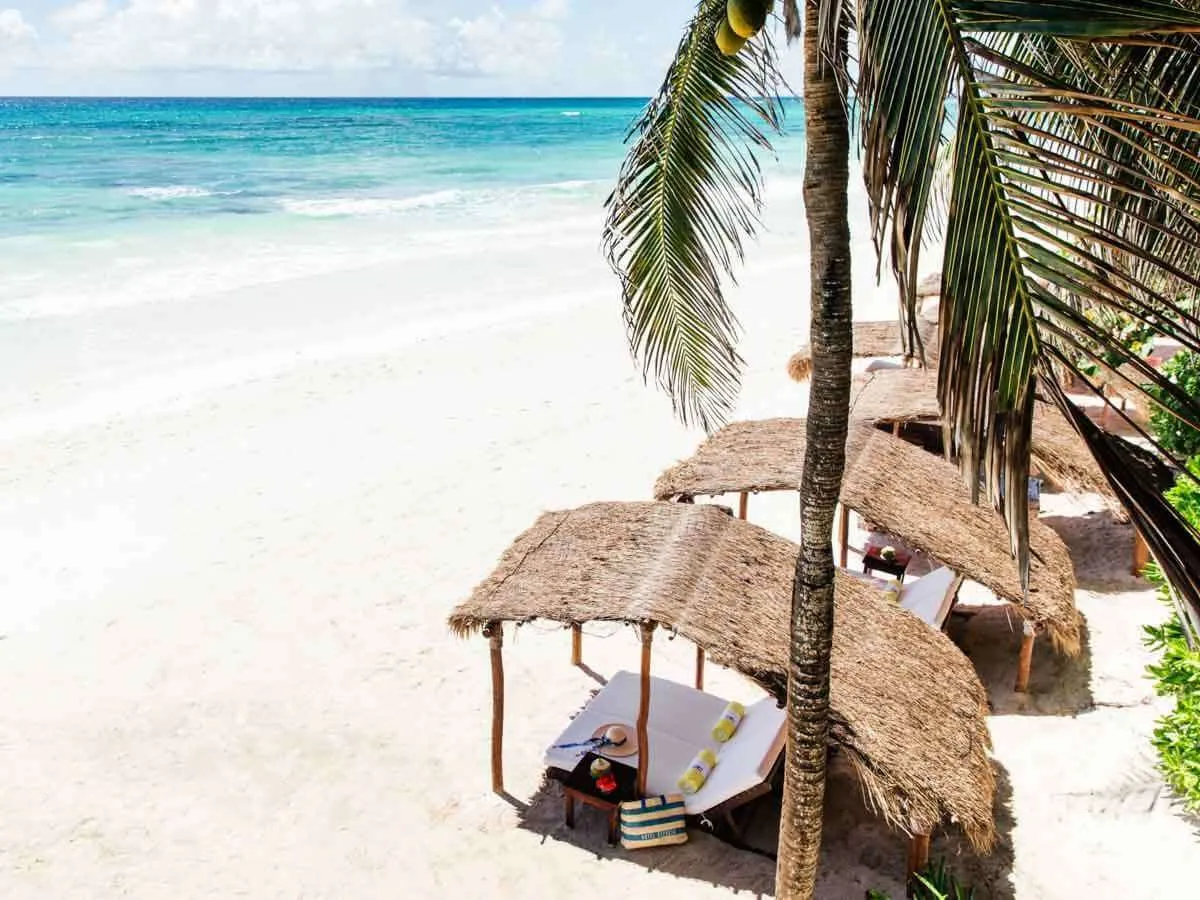 The beach at Hotel Esencia Playa del Carmen luxury boutique hotel with lounge beds with a thatched roof shade