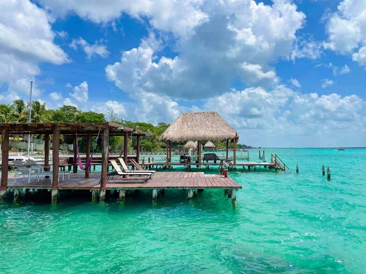 A wooden dock with lounge chairs over the water at Bacalar Lagoon