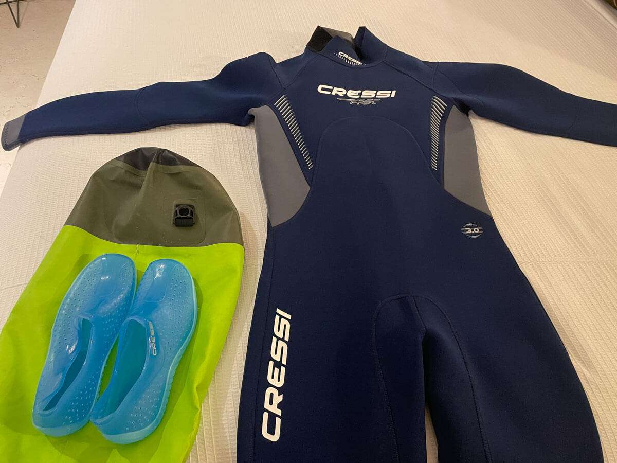 A wetsuit and water shoes laid out on a bed before a Holbox bioluminescence tour