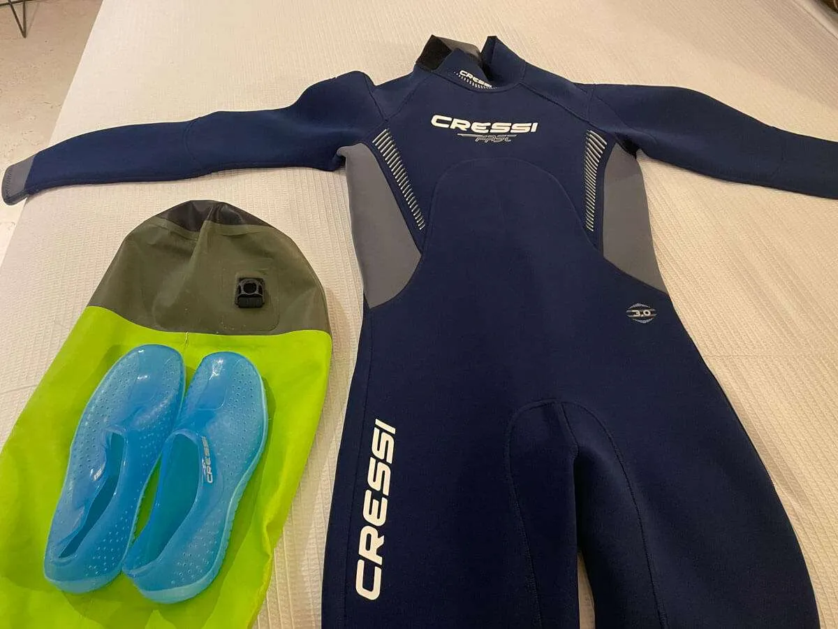 A wetsuit and water shoes laid out on a bed before a Holbox bioluminescence tour