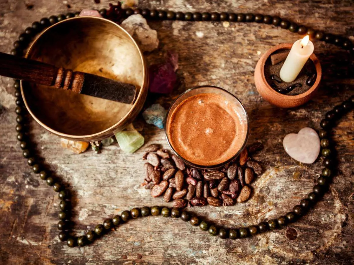A bowl with a liquid and a candle on top of cacao beans during a Holbox cacao ceremony