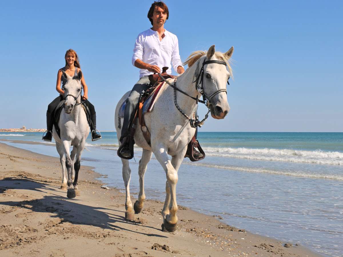 A couple horseback riding on the beach in Holbox Mexico