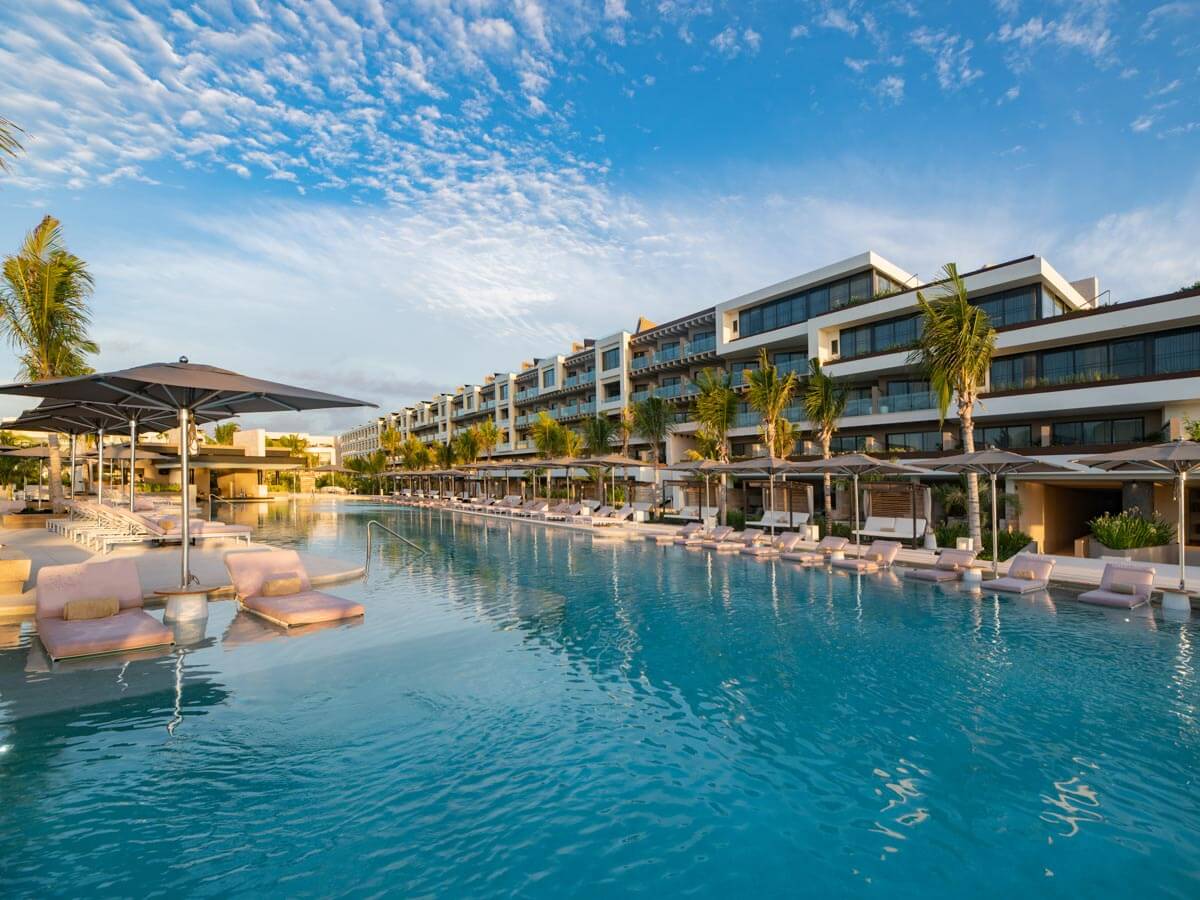 Lounge beds next to the pool and resort buildings at Atelier Playa Mujeres All-Inclusive Mexico Resort