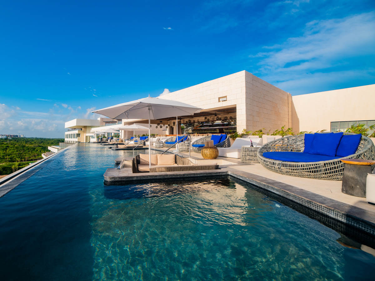 Lounge beds and umbrellas next to the rooftop pool at Atelier Playa Mujeres