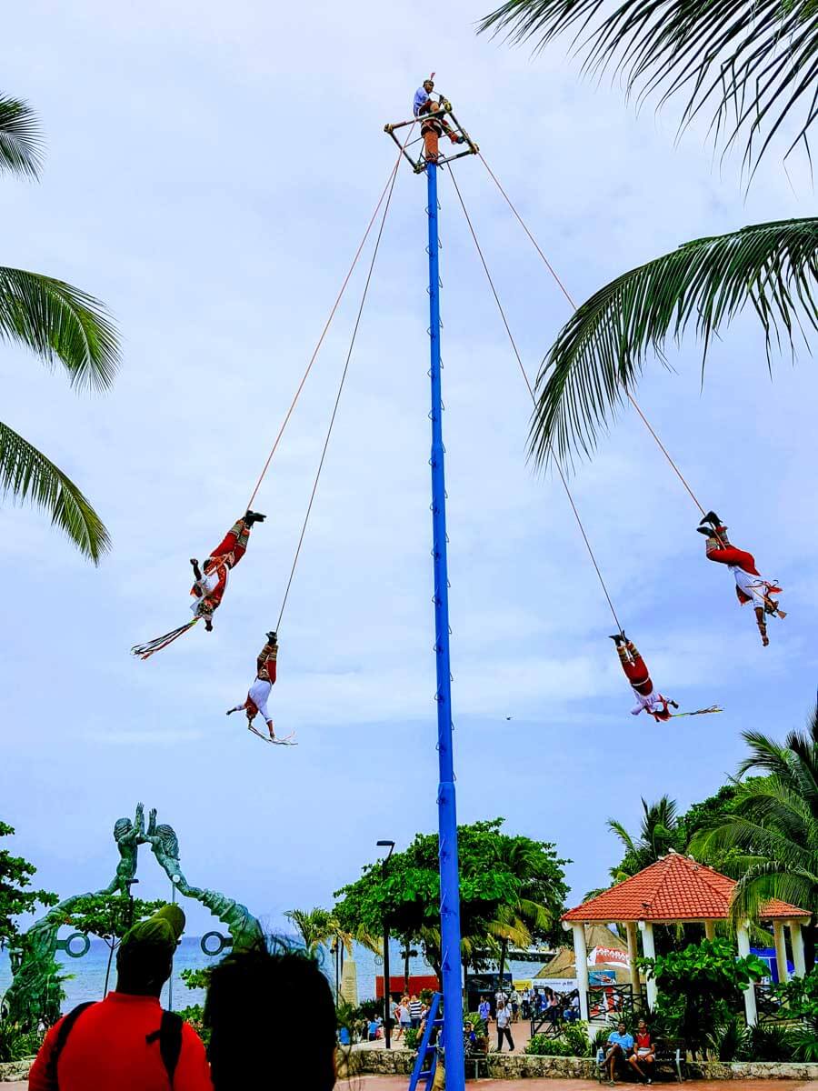 The Papantla performers swinging upside down from a tall pole in Playa del Carmen Mexico