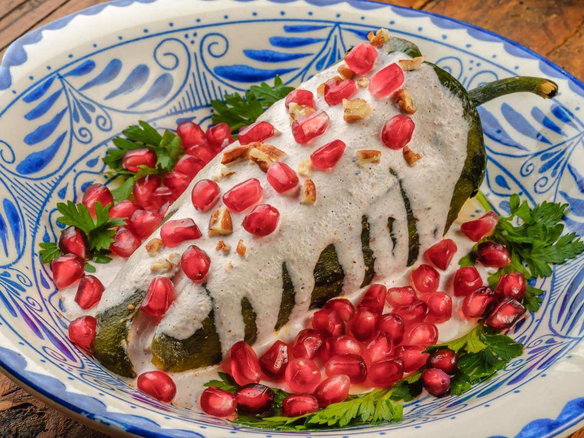 A plate of chile en nogada topped with walnuts and pomegranate seeds from Puebla Mexico