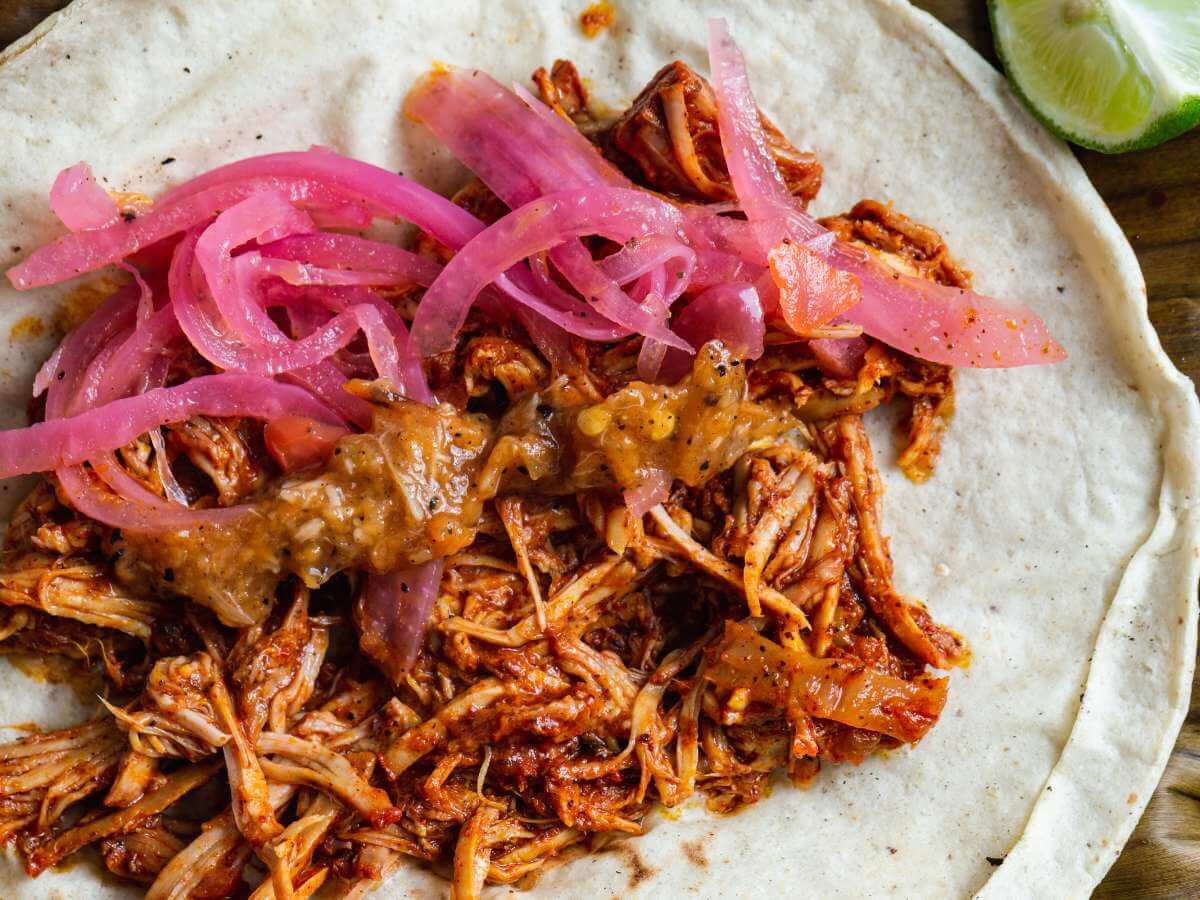 A plate of cochinita pibil tacos topped with pickled onions from Merida Mexico