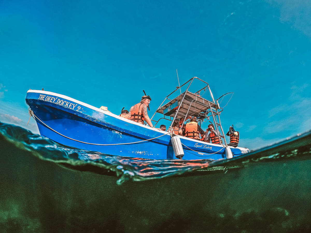 A small boat full of snorkelers wearing orange life jackets