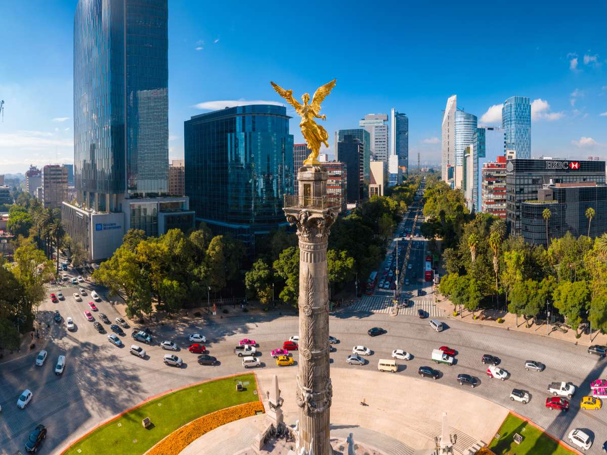 An aerial view of the Angel of Independence Statue in Mexico City surrounded by cars and modern buildings