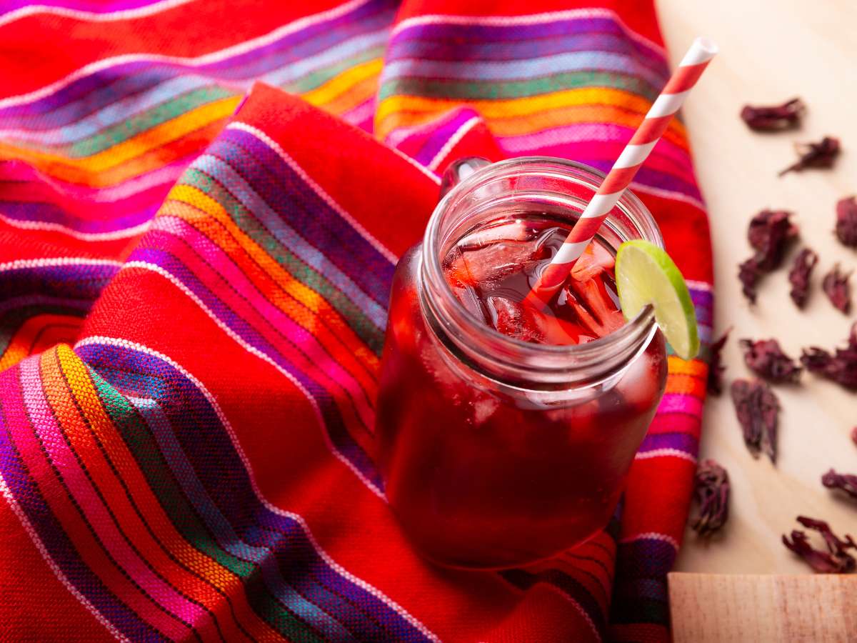 A glass of agua de jamaica sitting on top of a colorful Mexican blanket