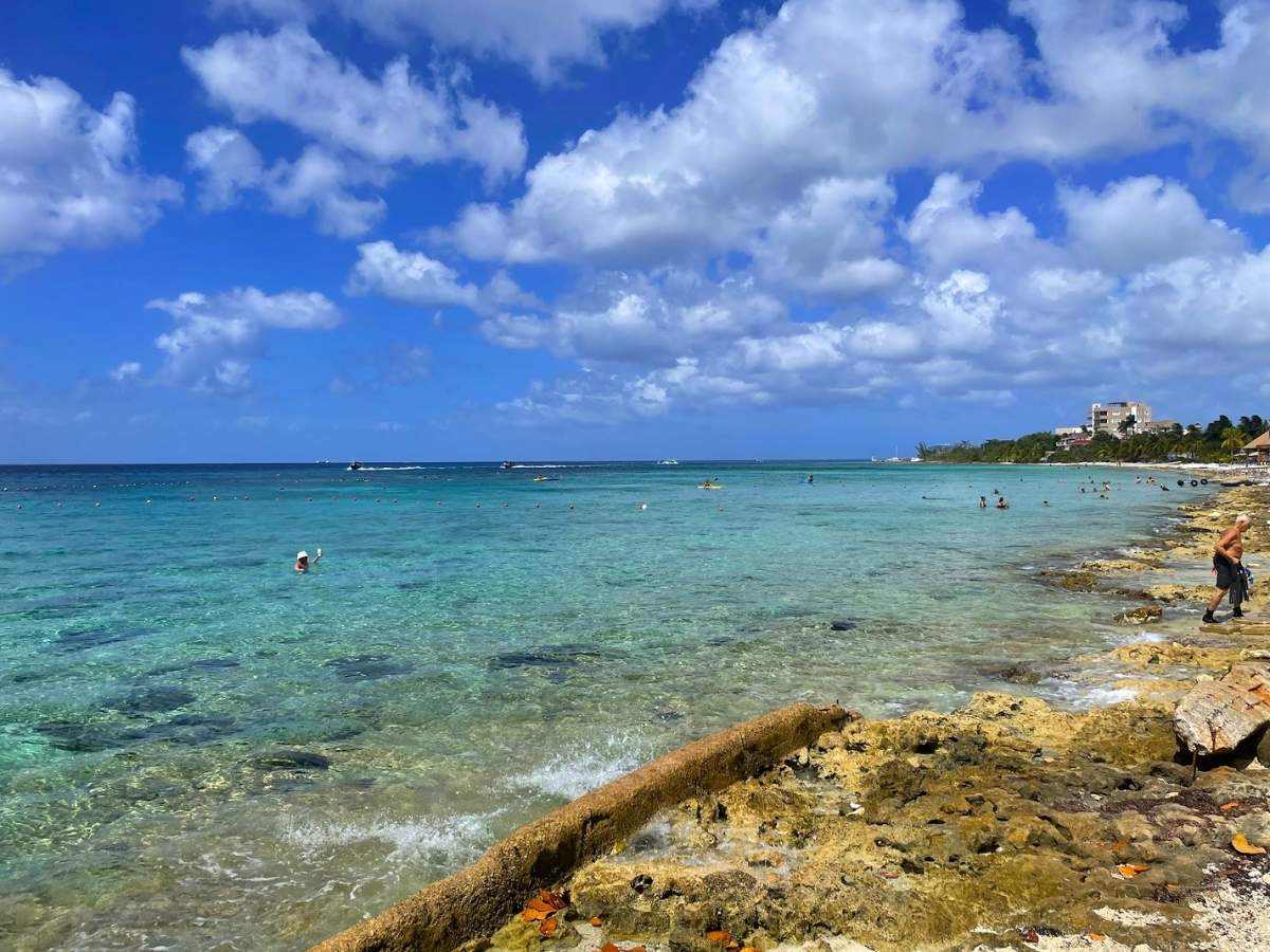 A rocky coastline in Cozumel Mexico with people swimming and snorkeling in the water