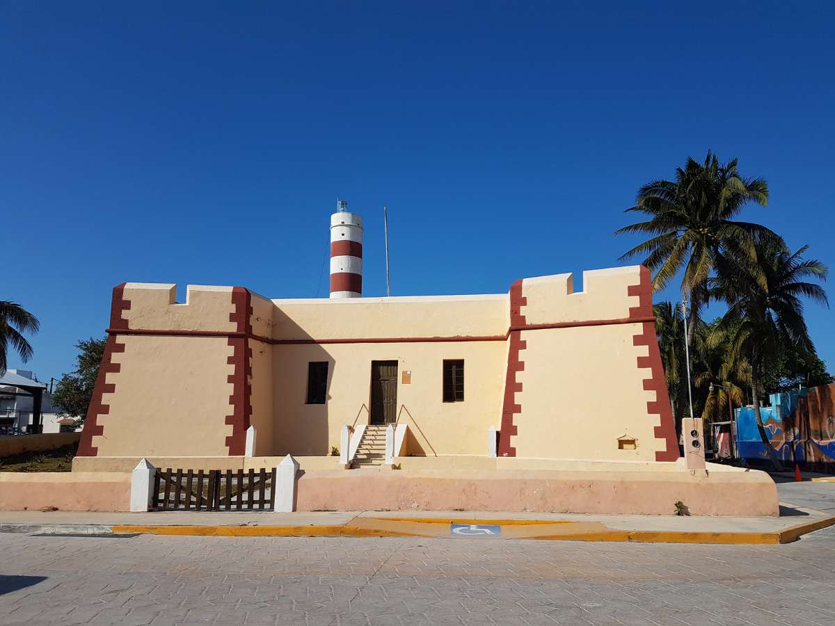 The lighthouse in Sisal Mexico surrounded by palm trees